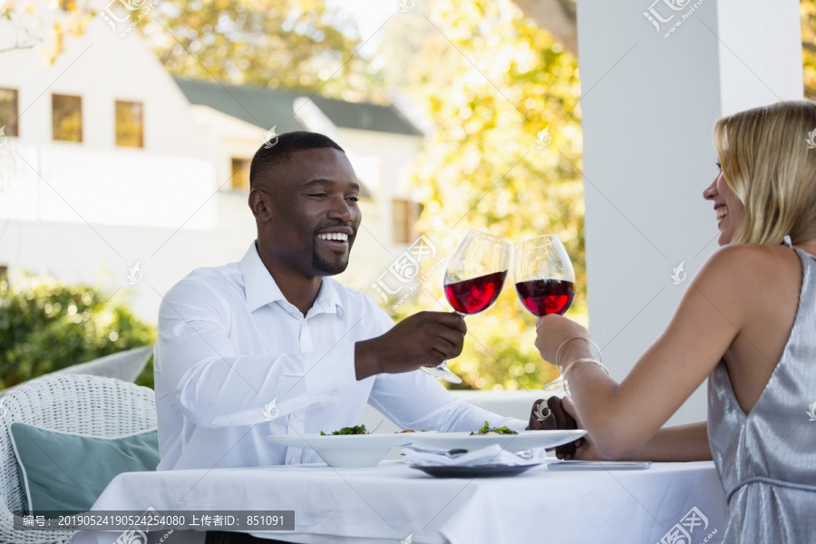 年轻夫妇坐在餐馆里烤红酒