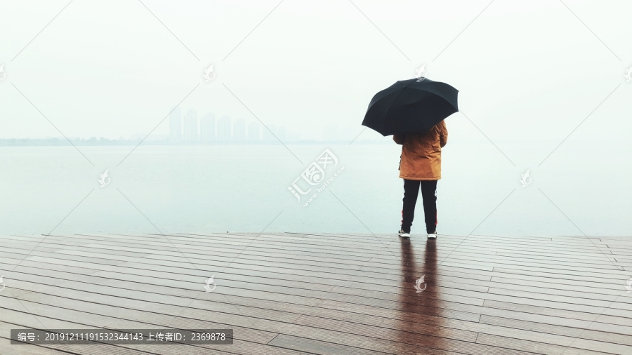 小雨时湖边打伞的男孩背影