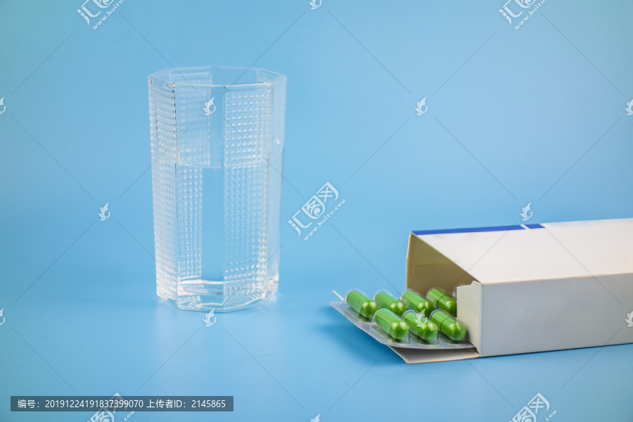 蓝色背景中放着水杯和药品