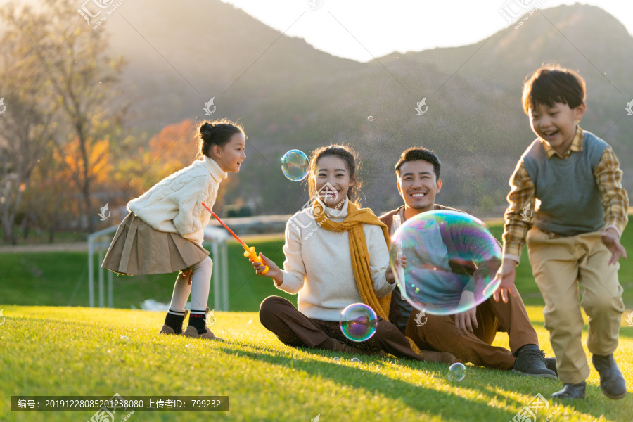 年轻夫妻和孩子们在草地上玩泡泡