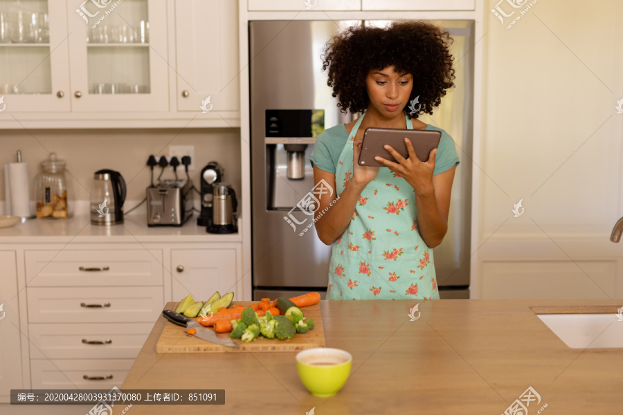 妇女站在厨房里使用平板电脑