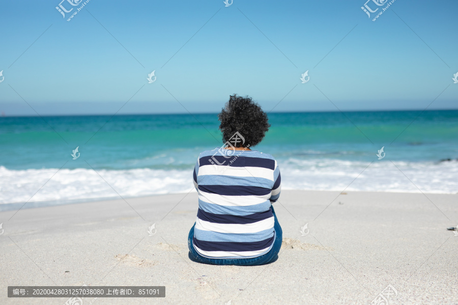 老太太坐在沙滩上仰望地平线
