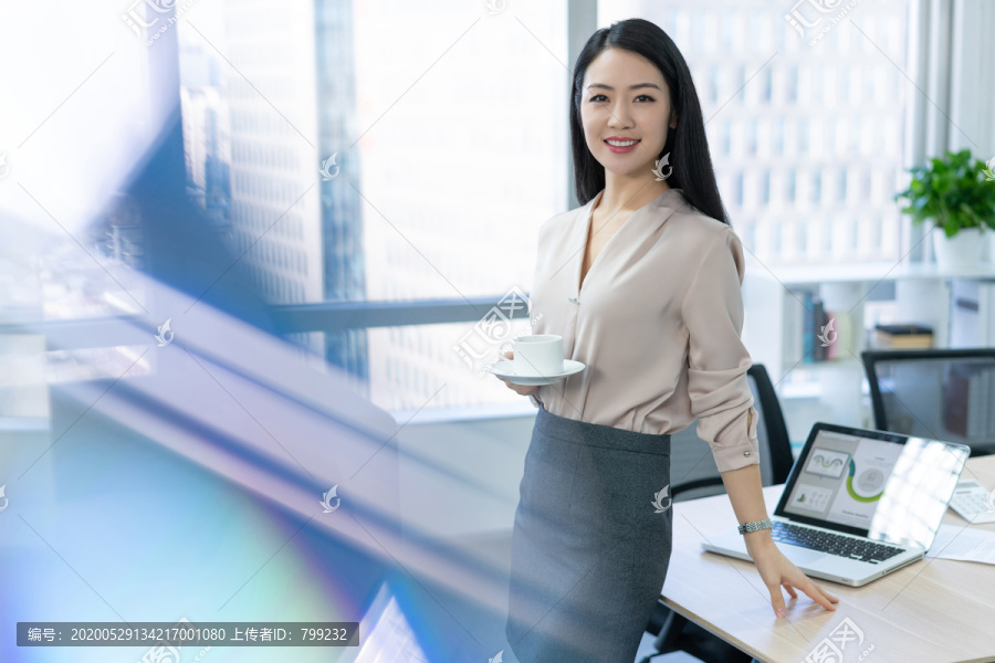 年轻商务女士在办公室喝咖啡