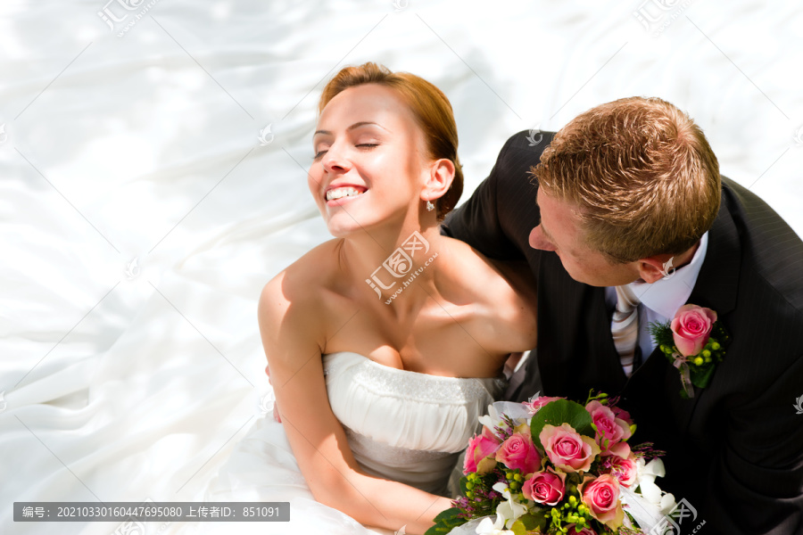 新婚夫妇拥抱着，新娘手里拿着一束鲜花，新郎拥抱着她