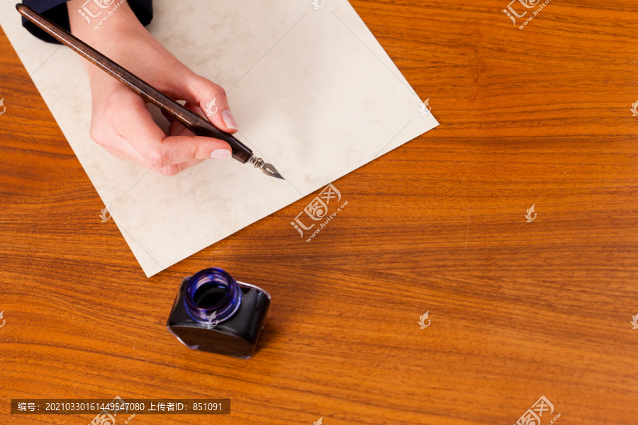 用钢笔和墨水在纸上写信的女人（只看到一只手）