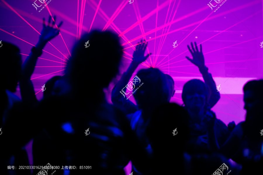 舞者在迪斯科俱乐部举行庆祝活动的剪影，灯光秀在背光场景中发射激光束，聚焦在光束上！