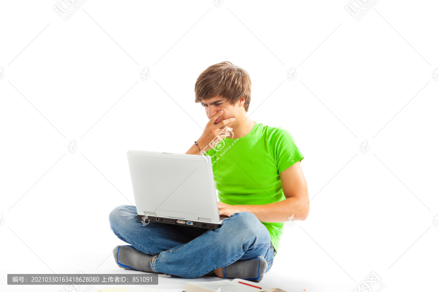 一个年轻人坐在地上，两腿交叉，拿着笔记本电脑，正在工作