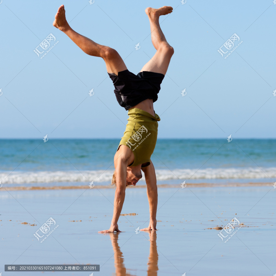 在海滩上做体操的运动型年轻人