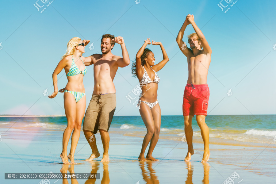 四个朋友-男人和女人-在海滩上享受他们的假期在水中跳跃的乐趣