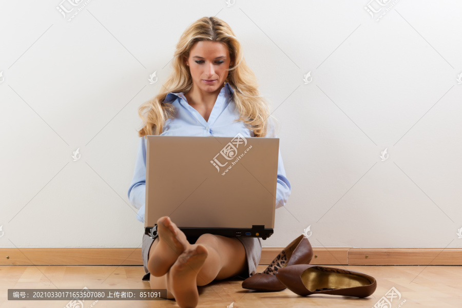 在家工作的女商人把笔记本电脑放在地板上