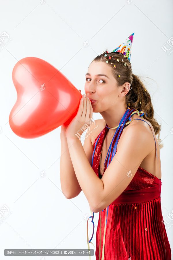 庆祝生日或情人节的女人，戴着派对帽手持心形气球