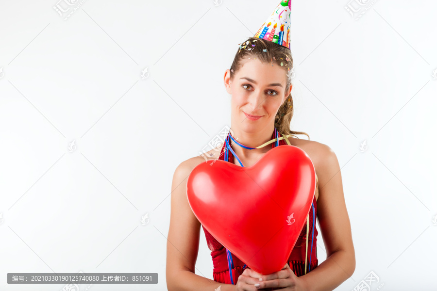 庆祝生日或情人节的女人，戴着派对帽手持心形气球