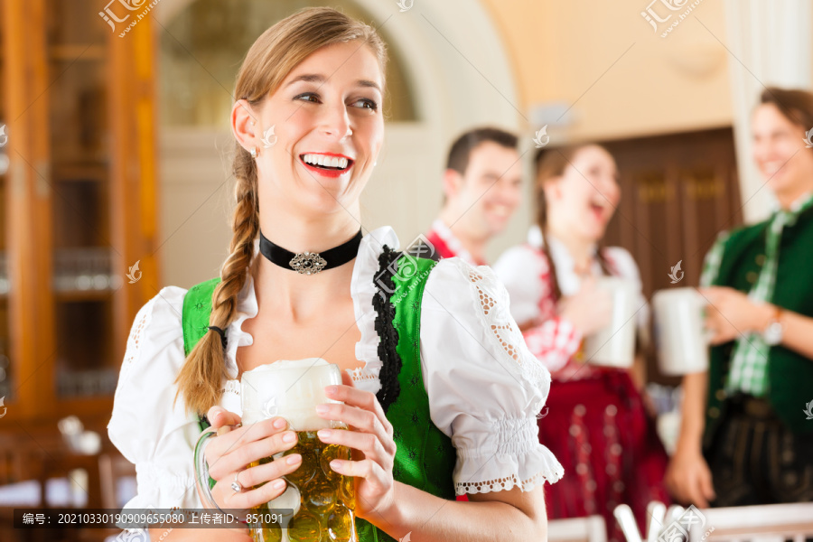 年轻人在传统的巴伐利亚餐馆或酒吧里，一个女人正站在啤酒史坦面前，一群人在后面