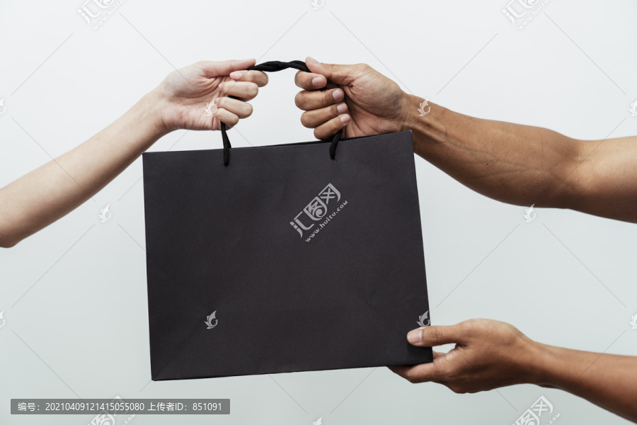 人们手举白色背景的黑色购物纸袋。