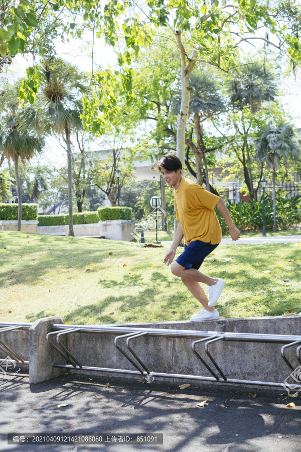 穿黄色t恤和蓝色裤子的男孩在绿色公园玩得很开心。