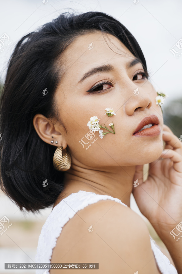 性感亚洲女孩的特写肖像，两颊上有一束小花。