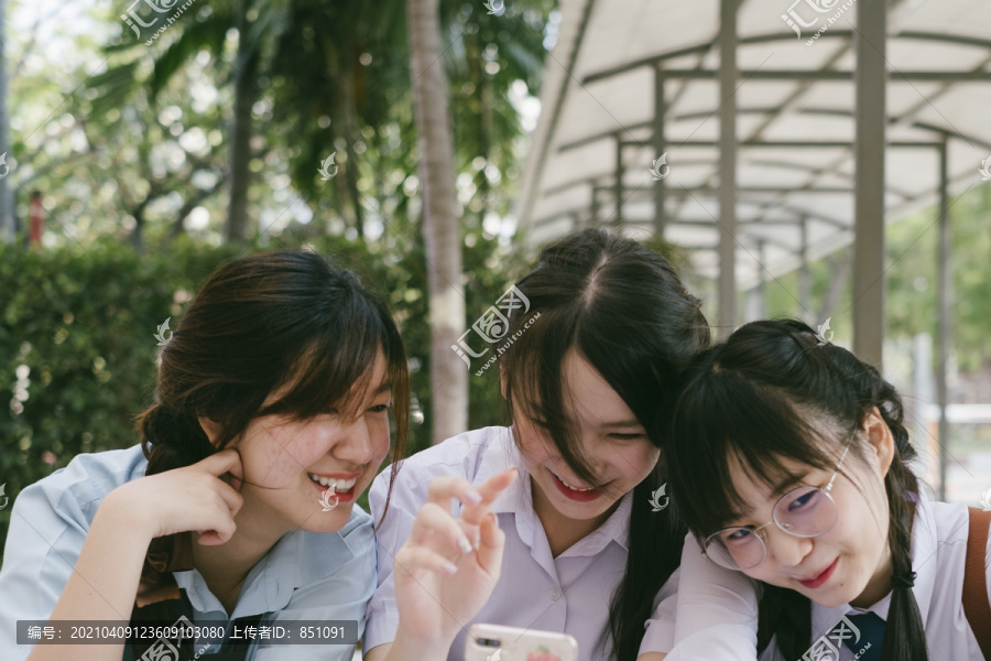 三个穿着不同制服的美丽亚泰学生在学校玩得很开心的特写镜头。