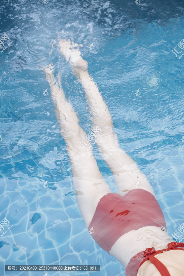 穿着红色比基尼的泰国美女美腿在泳池里游泳。