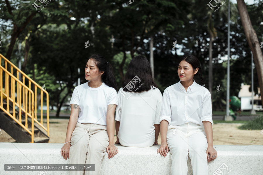 三对双胞胎妹妹坐在公园操场的大理石长凳上。