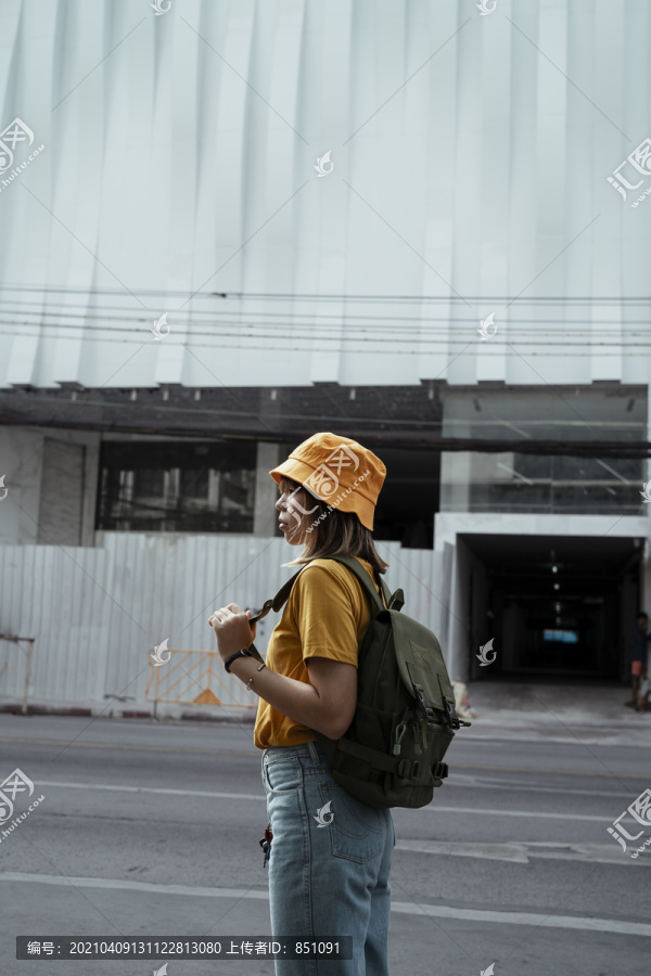 黄色背包女，背着绿色背包，站在施工区前。