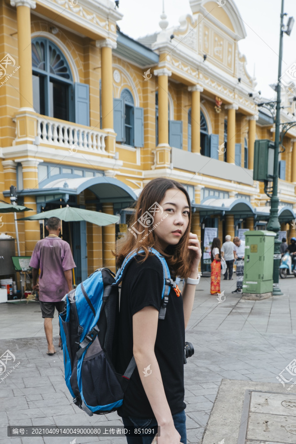 穿黑衬衫的背包女在曼谷用智能手机旅行。