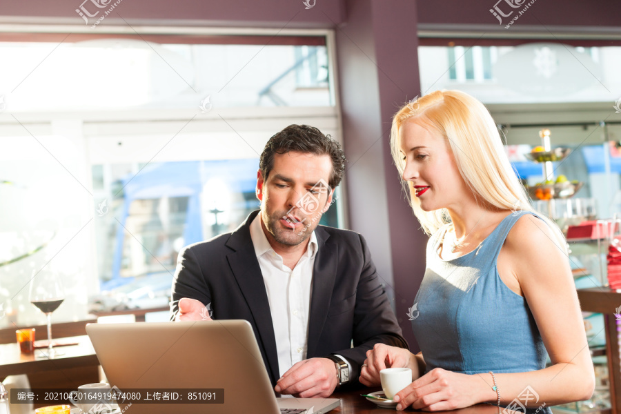 工作同事——一男一女——坐在咖啡馆里工作，喝着咖啡
