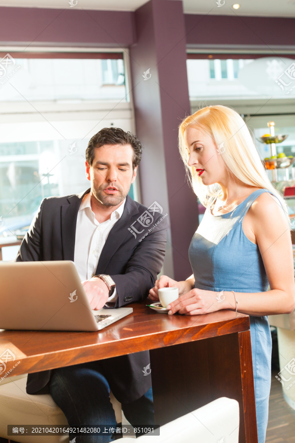 工作同事——一男一女——坐在咖啡馆里工作，喝着咖啡