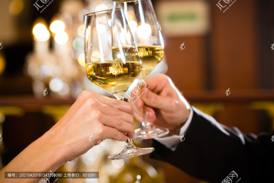 这对幸福的情侣在一家高级餐厅有一次浪漫的约会，他们喝着葡萄酒，碰杯，干杯-特写镜头