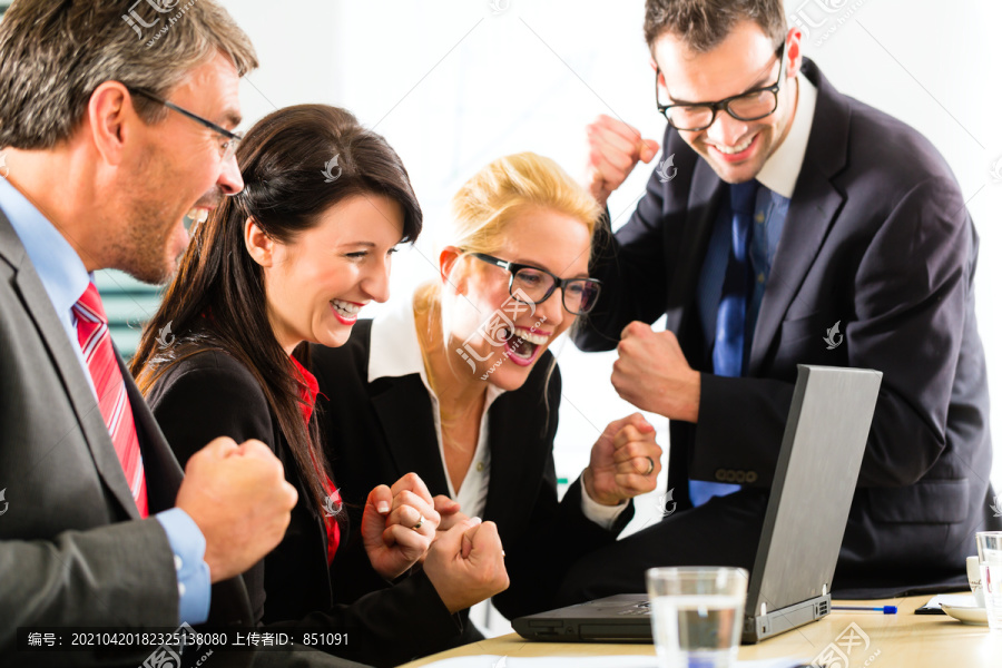 商务——四位身着商务装的职场人士一起看着笔记本电脑屏幕，他们欣喜若狂