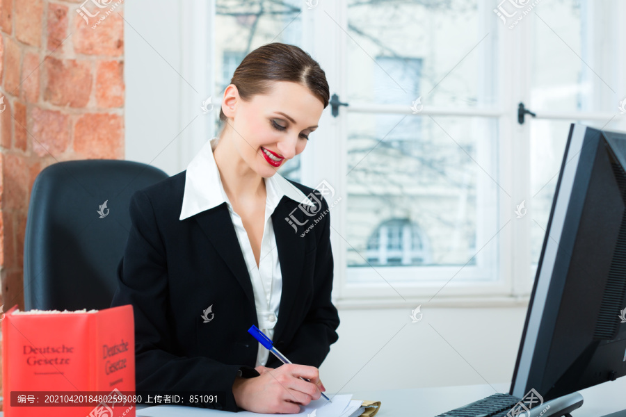 年轻的女律师拿着一本典型的法律书在办公室工作，写着一份文件