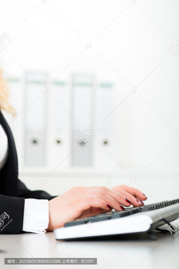 在办公室工作的年轻律师或女商人，她用电脑和键盘写字