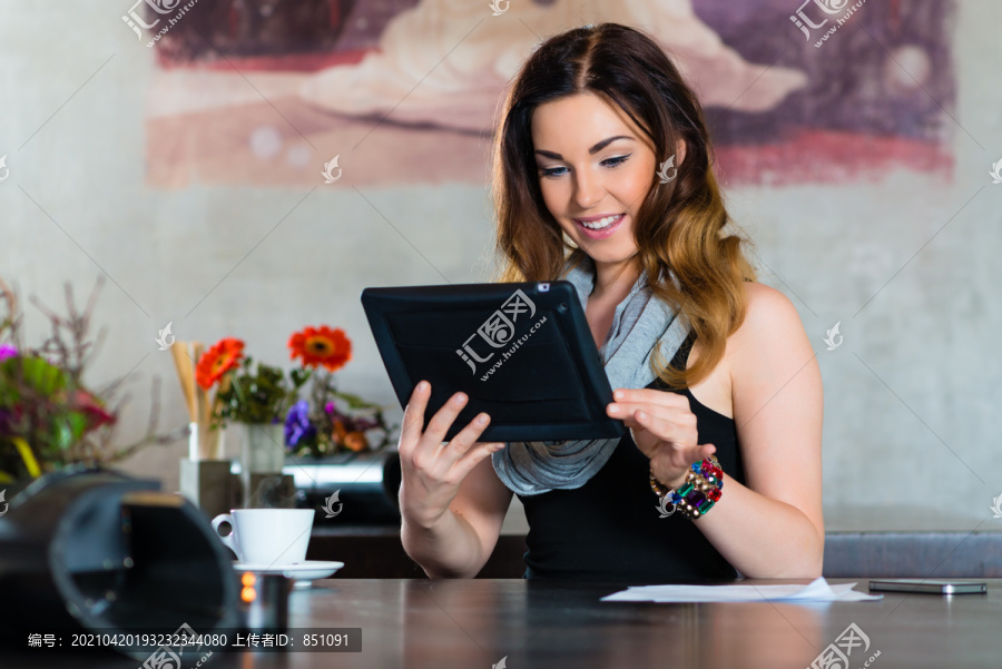 年轻女子在咖啡馆或餐厅，她用她的平板电脑电子邮件和视频聊天