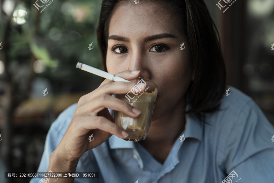 特写亚泰妇女吸烟和喝咖啡拿铁从玻璃杯。