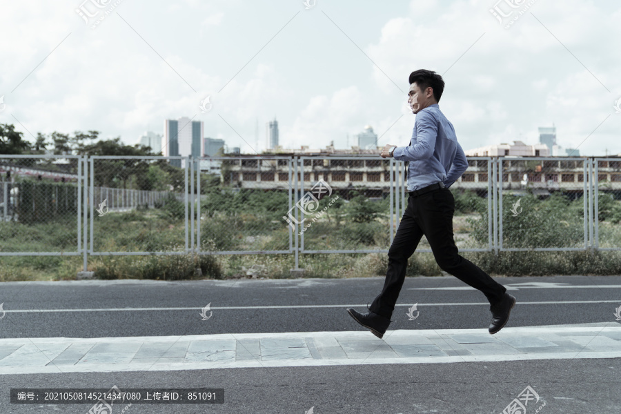 亚洲商人在公路上匆忙奔跑的侧影。