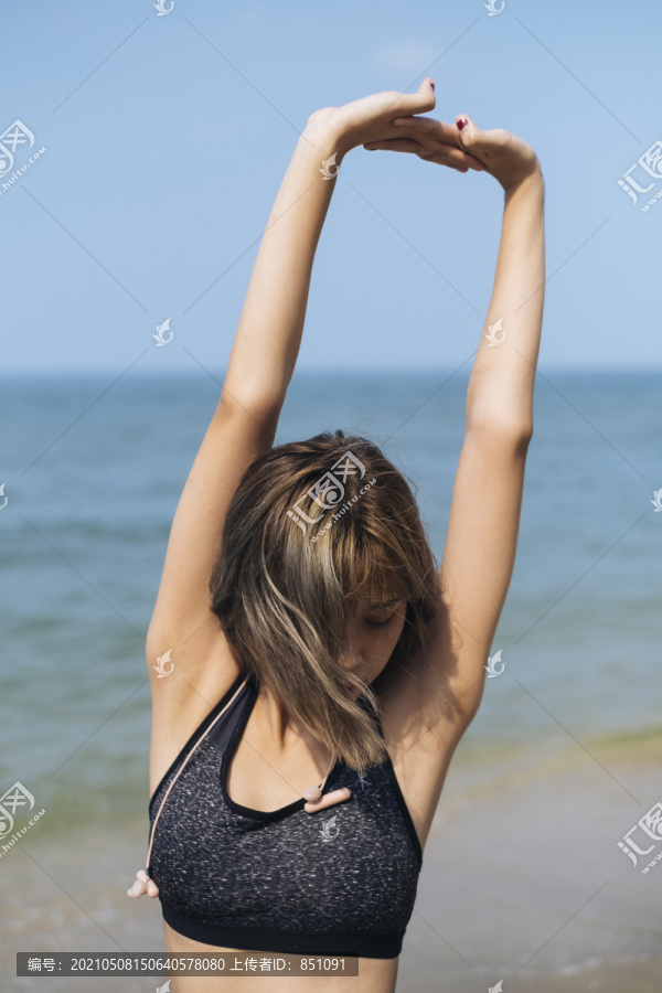 短发运动型女人在沙滩上伸展和做瑜伽。