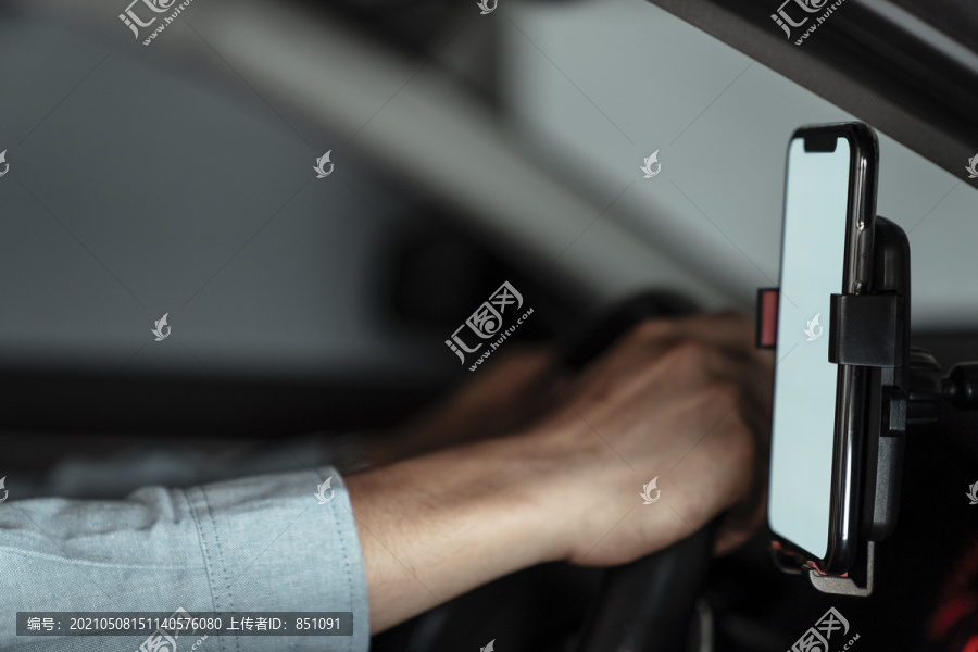 截图导航装置在前玻璃在汽车与男子的手紧紧握住方向盘。