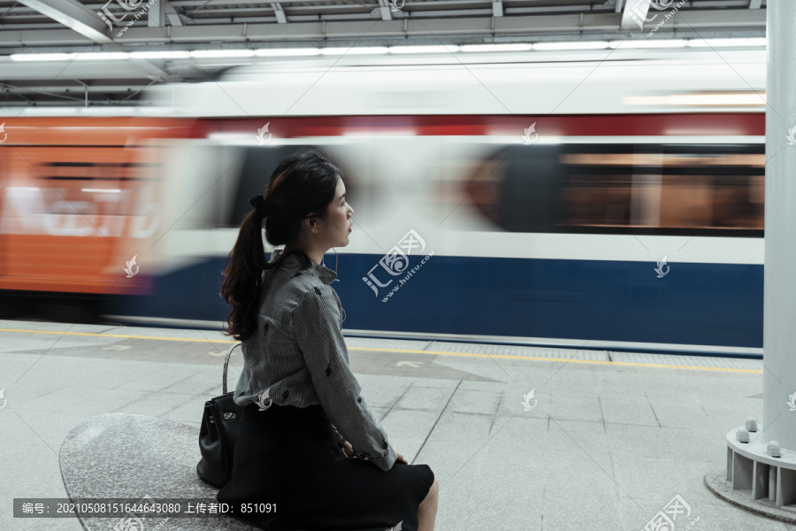 后视图-亚泰妇女等待火车回家在曼谷的火车站台在晚上。