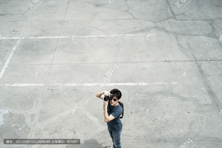 顶视图-年轻英俊的亚洲摄影师男子走在水泥地面上的城市-复制空间。