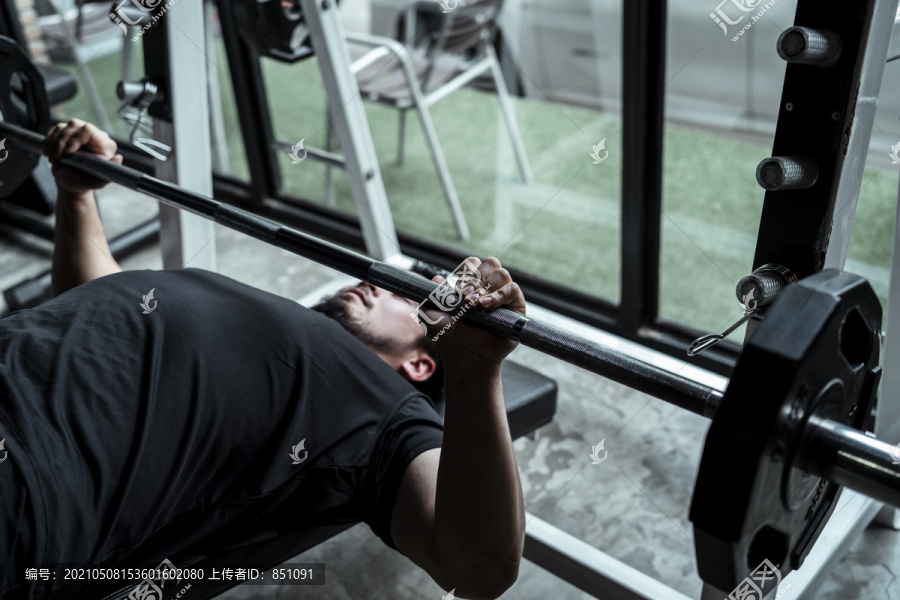 运动员亚泰体育男子闭着眼睛在健身房的杠铃台上练习。
