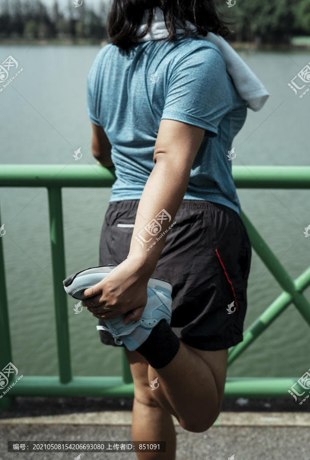 后视图-胖乎乎的运动型亚洲女性，穿着蓝色运动服，后腿伸展。