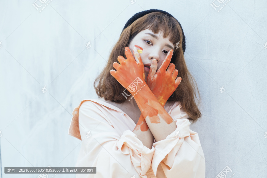美丽的时髦亚泰艺术家在长衬衫。橙色液体的脏手。肮脏的艺术家。橙色的手。
