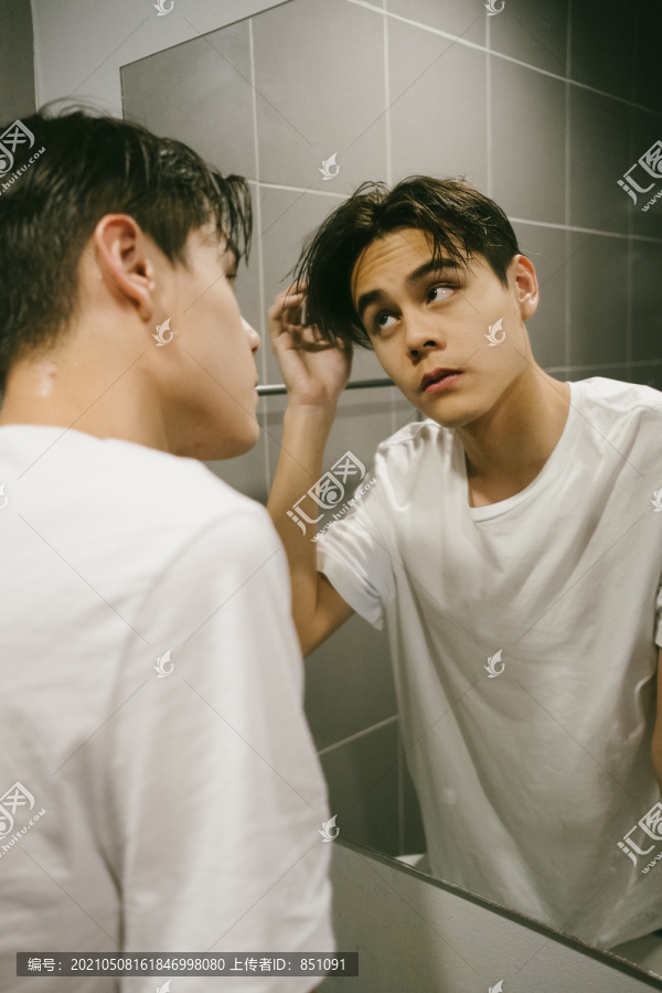 可爱的家伙在镜子前摸他湿漉漉的头发。
