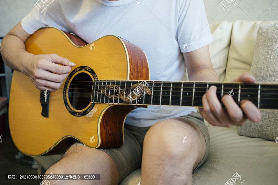 在客厅里的沙发上玩原声吉他的特写镜头。