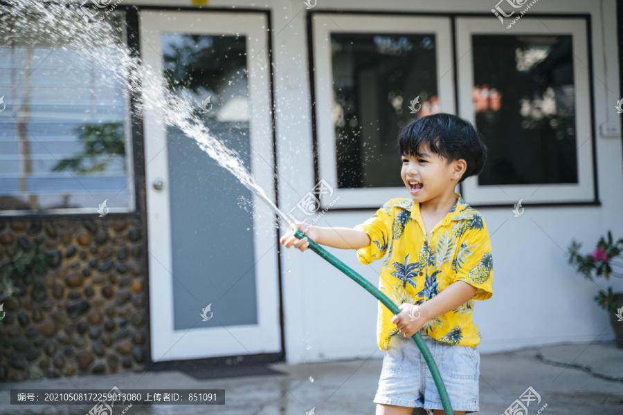 泰国一年一度的传统节日“泼水节”，一个小男孩在他家里用水枪和橡皮管泼水。