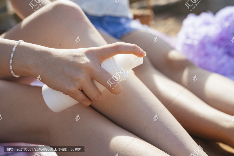在海上旅行时，女人的手在腿上喷防晒霜的剪短图像。