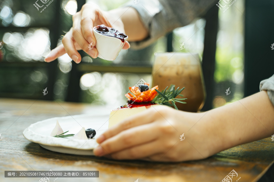 一位糕点女厨师正在往芝士蛋糕里倒草莓酱。甜点快乐。