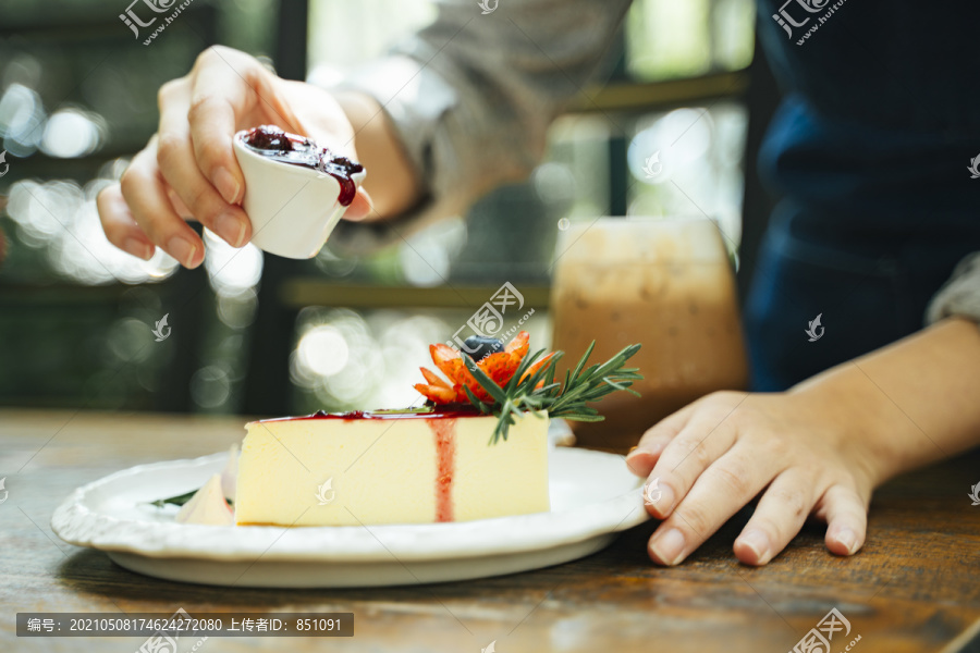 一位糕点女厨师正在往芝士蛋糕里倒草莓酱。甜点快乐。