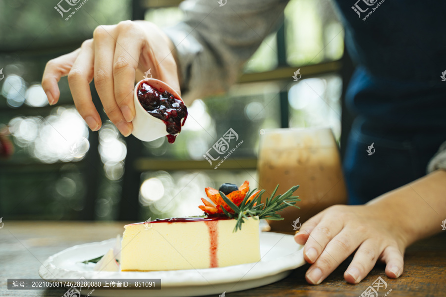 一位糕点女厨师正在往芝士蛋糕里倒草莓酱。甜点快乐。