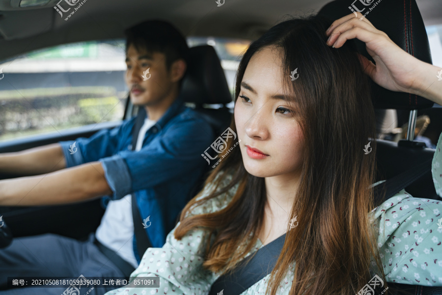 坐在乘客座位上的疲惫的年轻亚泰妇女。因为开车旅行而筋疲力尽。