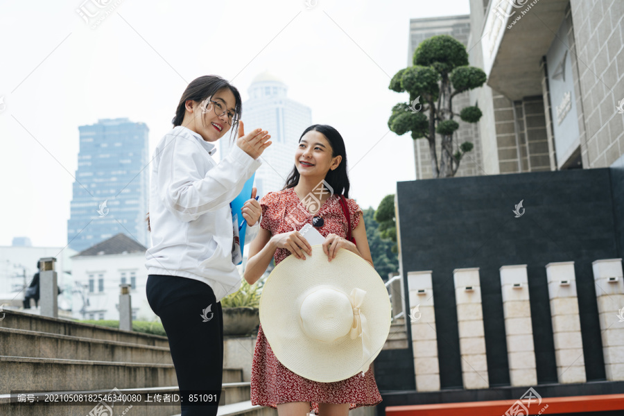 年轻开朗美丽的亚洲女子和导游在城市里散步。